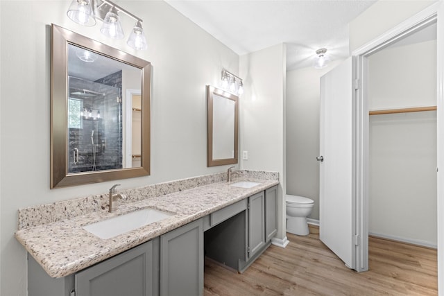 5 Cat Feet Ct, Spring, TX 77381 - bathroom featuring wood finished floors, double vanity, a walk in closet, and a shower
