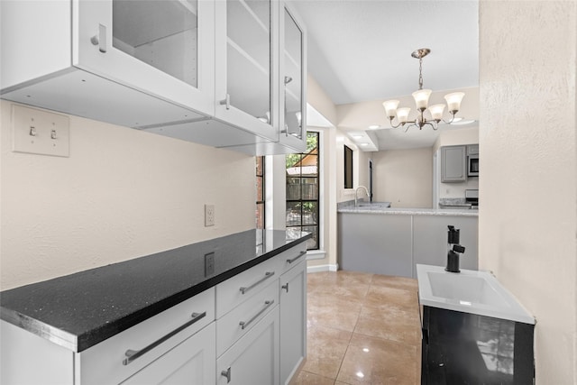 5 Cat Feet Ct, Spring, TX 77381 - kitchen featuring stainless steel microwave, light tile patterned flooring, a chandelier, glass insert cabinets, and white cabinets