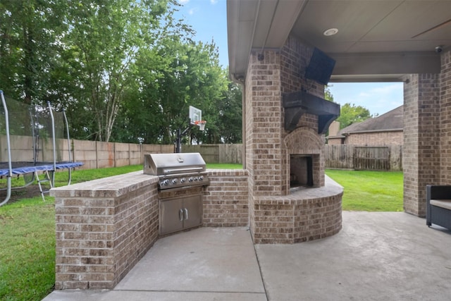 100 Anderson Ranch Ln, Friendswood, TX 77546 - fenced backyard with an outdoor brick fireplace, exterior kitchen, a trampoline, and a patio area