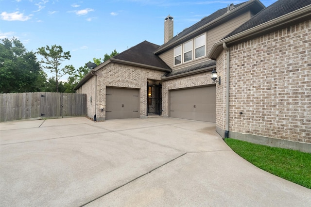 100 Anderson Ranch Ln, Friendswood, TX 77546 - view of home's exterior featuring concrete driveway, a garage, brick siding, and a chimney