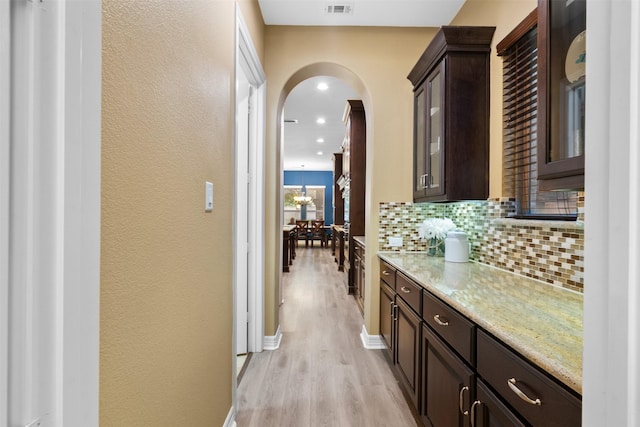 100 Anderson Ranch Ln, Friendswood, TX 77546 - bar area with arched walkways, light wood-type flooring, backsplash, and a textured wall