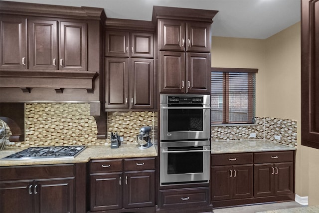 100 Anderson Ranch Ln, Friendswood, TX 77546 - kitchen featuring appliances with stainless steel finishes, backsplash, dark brown cabinets, and light stone counters