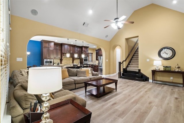 100 Anderson Ranch Ln, Friendswood, TX 77546 - living room featuring arched walkways, ceiling fan, stairs, light wood finished floors, and high vaulted ceiling