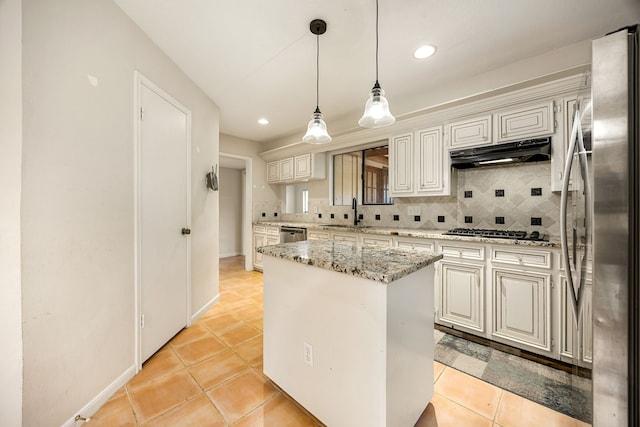 8020 Oakwood Forest Dr, Houston, TX 77040 - kitchen with appliances with stainless steel finishes, under cabinet range hood, backsplash, a kitchen island, and light tile patterned floors