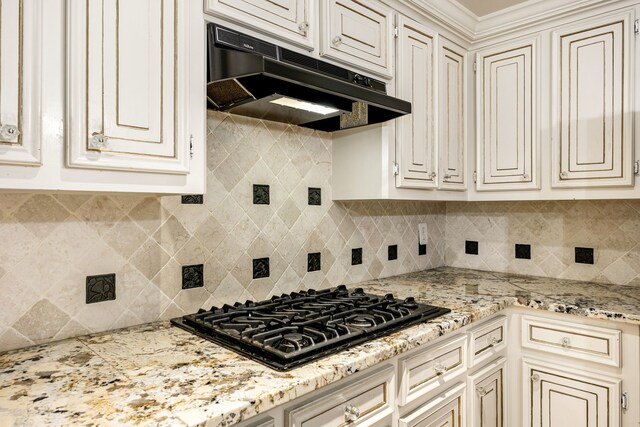 8020 Oakwood Forest Dr, Houston, TX 77040 - kitchen featuring under cabinet range hood, black gas stovetop, cream cabinets, and decorative backsplash