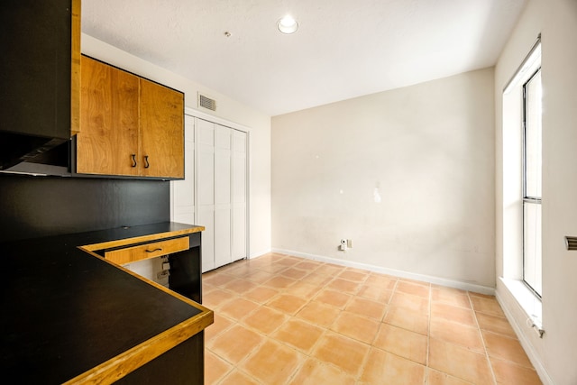 8020 Oakwood Forest Dr, Houston, TX 77040 - kitchen featuring dark countertops, brown cabinets, light tile patterned flooring, and recessed lighting