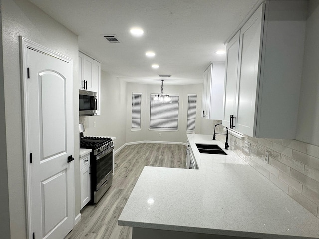 18468 Misty Wood Ln, Porter, TX 77365 - kitchen with stainless steel appliances, light wood-style flooring, decorative backsplash, white cabinetry, and recessed lighting