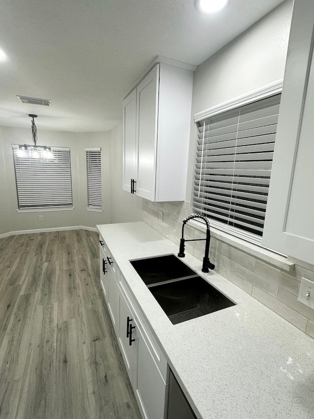 18468 Misty Wood Ln, Porter, TX 77365 - kitchen featuring decorative backsplash, white cabinetry, light wood-type flooring, a chandelier, and light stone counters