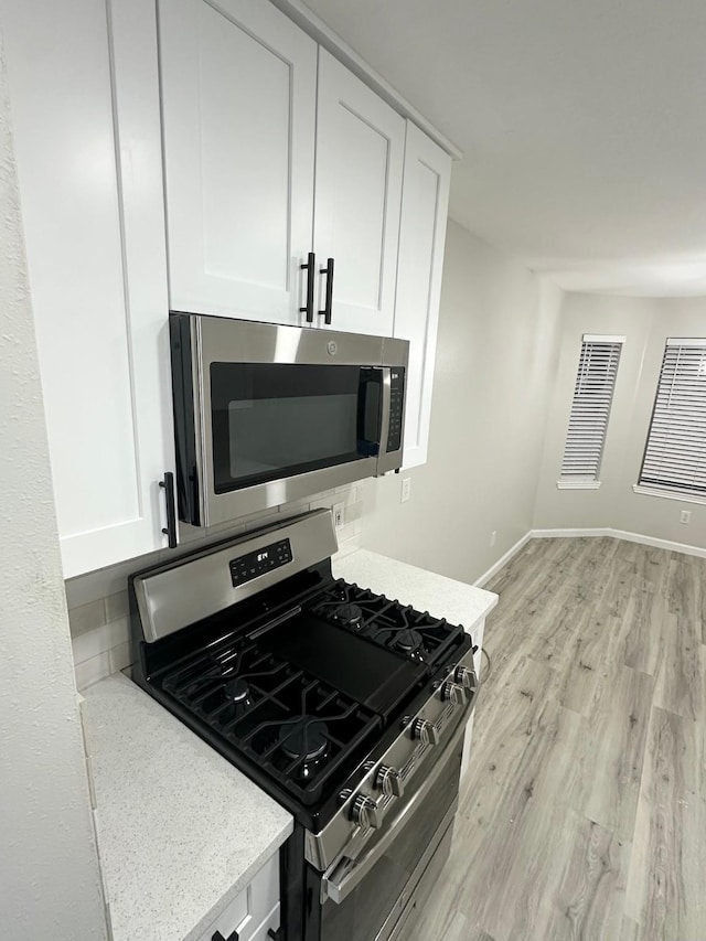 18468 Misty Wood Ln, Porter, TX 77365 - kitchen featuring stainless steel appliances, white cabinets, and light wood-style floors