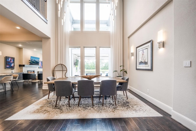 34207 Mill Creek Ct, Pinehurst, TX 77362 - dining area with a glass covered fireplace, plenty of natural light, a towering ceiling, and dark wood-type flooring