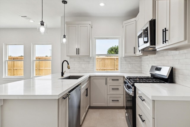 8614 Viera Ln, Houston, TX 77075 - kitchen with appliances with stainless steel finishes, a peninsula, recessed lighting, tasteful backsplash, and light stone counters