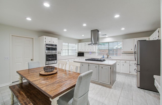 3411 Deeds Rd, Houston, TX 77084 - kitchen with stainless steel appliances, island range hood, light countertops, white cabinets, and a center island