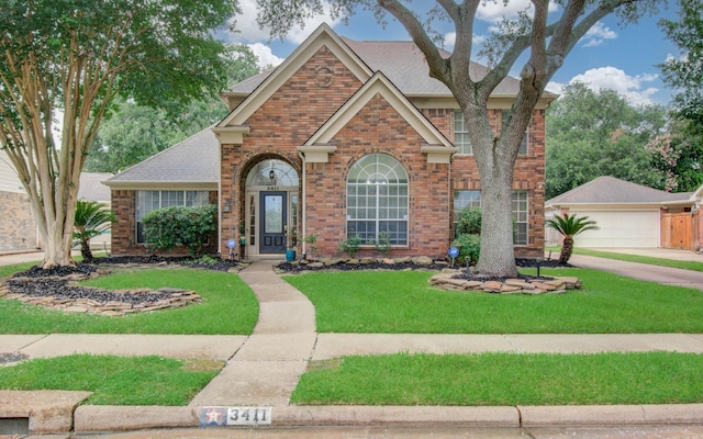3411 Deeds Rd, Houston, TX 77084 - traditional-style home featuring brick siding, a front lawn, a shingled roof, and a detached garage