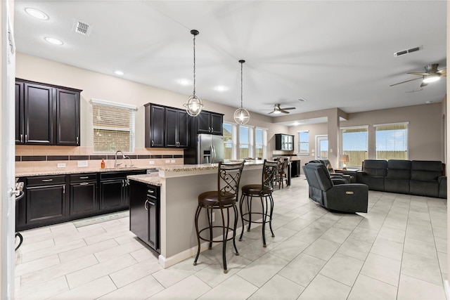19647 Travis Cannon Ln, Richmond, TX 77407 - kitchen featuring a ceiling fan, stainless steel refrigerator with ice dispenser, open floor plan, a kitchen bar, and recessed lighting