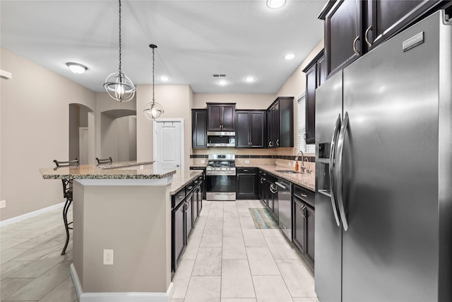 19647 Travis Cannon Ln, Richmond, TX 77407 - kitchen featuring stainless steel appliances, a center island, a breakfast bar, light stone countertops, and pendant lighting