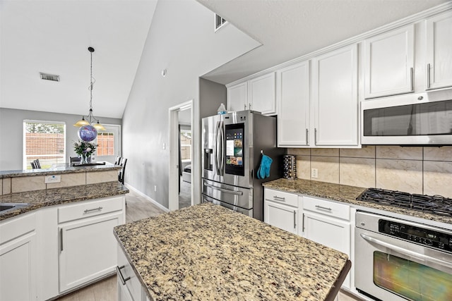 15323 Southwood Trace Ln, Houston, TX 77049 - kitchen featuring appliances with stainless steel finishes, white cabinets, dark stone countertops, light wood-style floors, and high vaulted ceiling