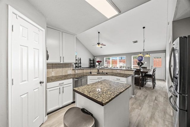 15323 Southwood Trace Ln, Houston, TX 77049 - kitchen featuring stainless steel appliances, a peninsula, white cabinets, hanging light fixtures, and a center island
