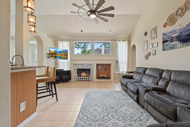 23 Murmuring Creek Pl, The Woodlands, TX 77385 - living room with a ceiling fan, arched walkways, light tile patterned floors, a tile fireplace, and high vaulted ceiling