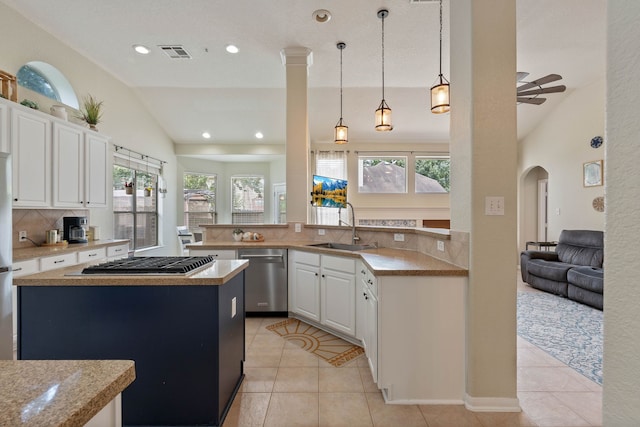 23 Murmuring Creek Pl, The Woodlands, TX 77385 - kitchen featuring appliances with stainless steel finishes, lofted ceiling, decorative backsplash, a center island, and arched walkways