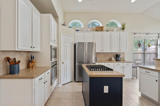 23 Murmuring Creek Pl, The Woodlands, TX 77385 - kitchen with stainless steel appliances, a kitchen island, plenty of natural light, white cabinets, and vaulted ceiling