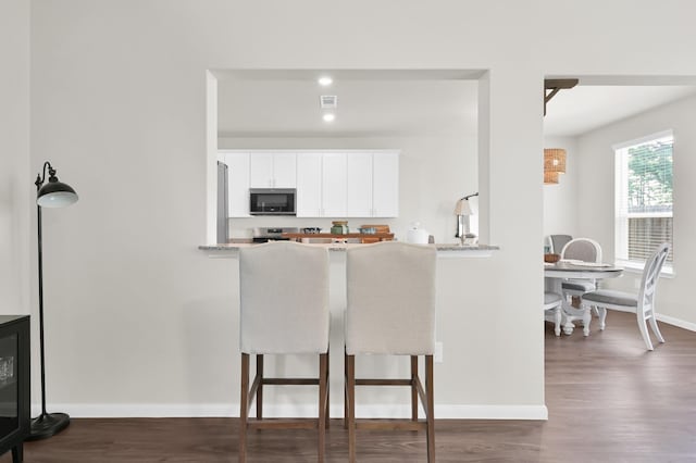 11739 Armadale Dr, Tomball, TX 77375 - kitchen featuring appliances with stainless steel finishes, dark wood-type flooring, a kitchen bar, and white cabinets