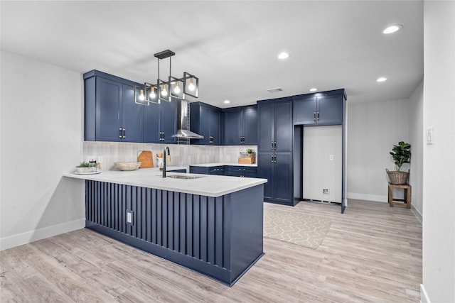 6935 Palmetto St, Houston, TX 77087 - kitchen featuring wall chimney range hood, blue cabinetry, light countertops, a peninsula, and recessed lighting