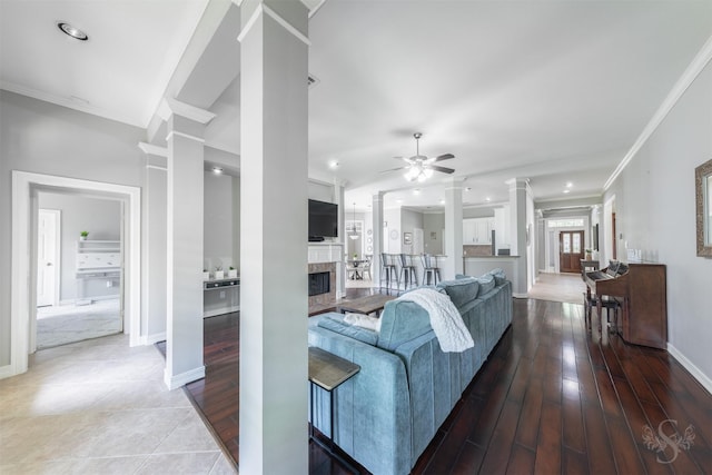 4611 Camden Brook Ln, Katy, TX 77494 - living room with decorative columns, a tiled fireplace, crown molding, a ceiling fan, and recessed lighting
