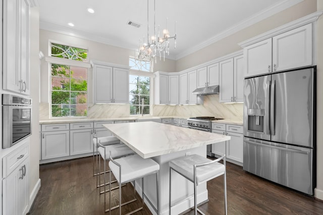 1801 Ashland St, Houston, TX 77008 - kitchen with appliances with stainless steel finishes, under cabinet range hood, a chandelier, tasteful backsplash, and a kitchen breakfast bar
