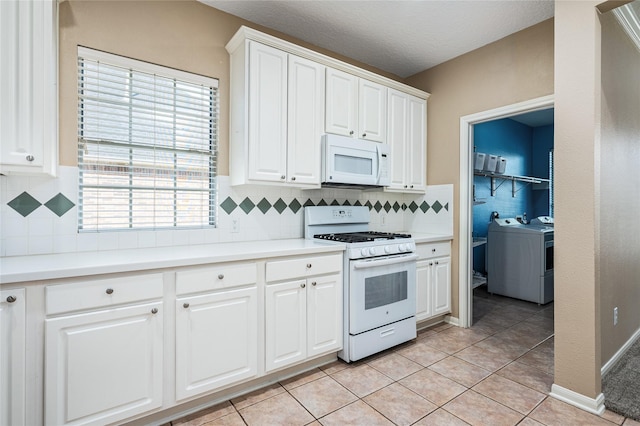 2603 Piney Woods Dr, Pearland, TX 77581 - kitchen with white appliances, separate washer and dryer, white cabinetry, and decorative backsplash