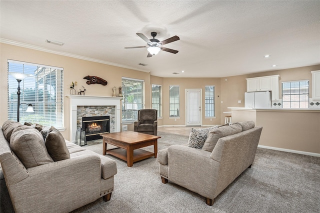 2603 Piney Woods Dr, Pearland, TX 77581 - living area featuring ceiling fan, plenty of natural light, a stone fireplace, a textured ceiling, and light colored carpet