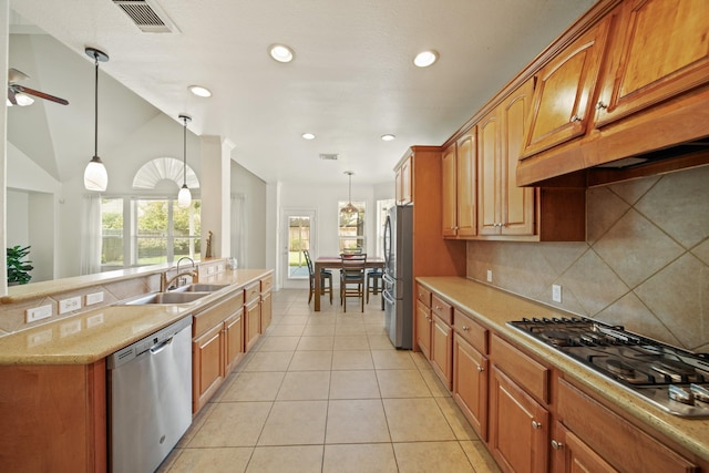4802 N Pine Brook Way, Houston, TX 77059 - kitchen with appliances with stainless steel finishes, backsplash, decorative light fixtures, light tile patterned floors, and brown cabinetry
