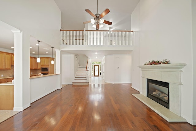 4802 N Pine Brook Way, Houston, TX 77059 - unfurnished living room featuring a ceiling fan, wood finished floors, a glass covered fireplace, a high ceiling, and stairs