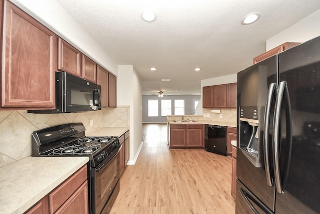 9914 Swallow Dr, Conroe, TX 77385 - kitchen with black appliances, light wood-style floors, light countertops, decorative backsplash, and ceiling fan