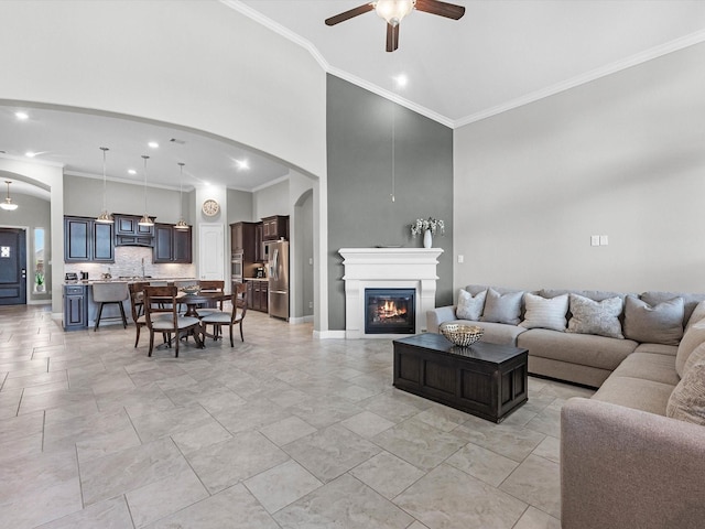 4623 Bisontine Bay Ln, Rosharon, TX 77583 - living room with ceiling fan, crown molding, a glass covered fireplace, arched walkways, and recessed lighting