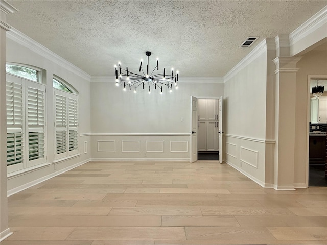 19 Pebble Hollow Ct, The Woodlands, TX 77381 - unfurnished dining area with a chandelier, light wood finished floors, ornamental molding, ornate columns, and a textured ceiling