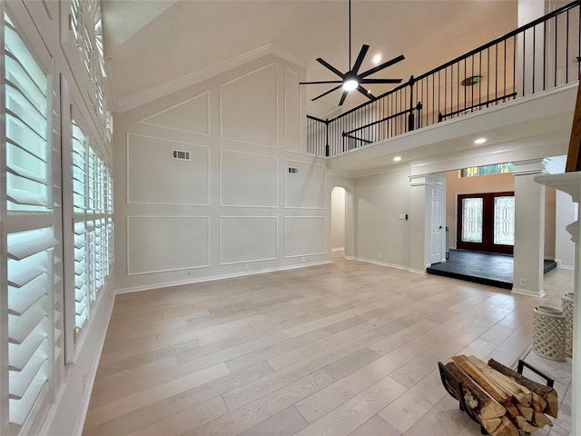 19 Pebble Hollow Ct, The Woodlands, TX 77381 - unfurnished living room featuring a decorative wall, ceiling fan, a high ceiling, arched walkways, and light wood-style flooring