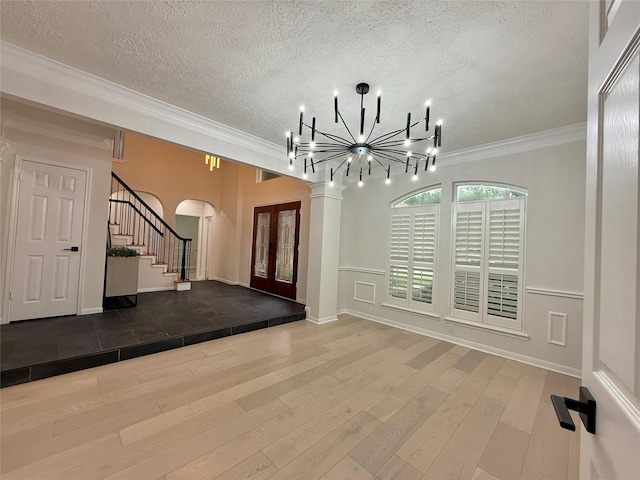 19 Pebble Hollow Ct, The Woodlands, TX 77381 - foyer with arched walkways, a chandelier, wood finished floors, a textured ceiling, and crown molding