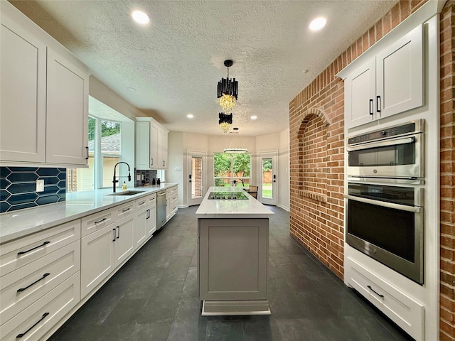 19 Pebble Hollow Ct, The Woodlands, TX 77381 - kitchen featuring appliances with stainless steel finishes, healthy amount of natural light, a center island, a textured ceiling, and tasteful backsplash