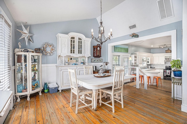 16615 Mansvelt Rd, Jamaica Beach, TX 77554 - dining space featuring vaulted ceiling, a chandelier, hardwood / wood-style floors, a wainscoted wall, and rail lighting