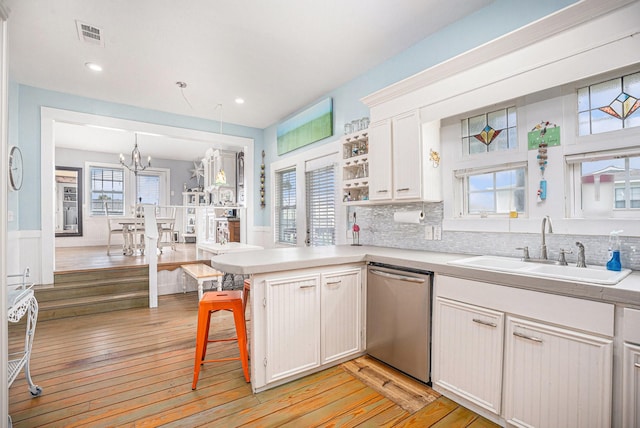16615 Mansvelt Rd, Jamaica Beach, TX 77554 - kitchen with dishwasher, a peninsula, light wood-style floors, a chandelier, and light countertops