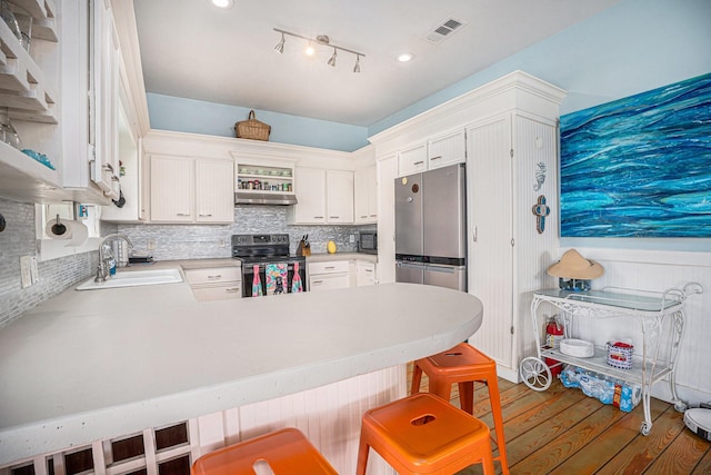 16615 Mansvelt Rd, Jamaica Beach, TX 77554 - kitchen with range with electric stovetop, freestanding refrigerator, wood finished floors, a peninsula, and decorative backsplash
