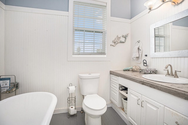 16615 Mansvelt Rd, Jamaica Beach, TX 77554 - bathroom featuring a soaking tub, vanity, healthy amount of natural light, wainscoting, and wood finished floors