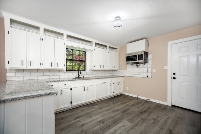 300 Duncan Ave, Lufkin, TX 75901 - kitchen featuring stainless steel microwave, tasteful backsplash, white cabinets, and dark wood finished floors