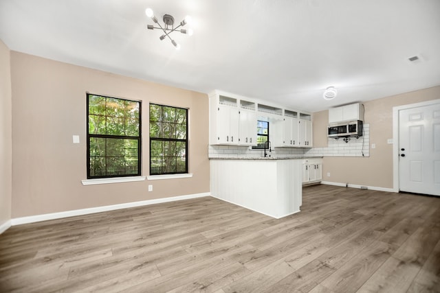 300 Duncan Ave, Lufkin, TX 75901 - kitchen featuring stainless steel microwave, white cabinetry, a peninsula, and tasteful backsplash
