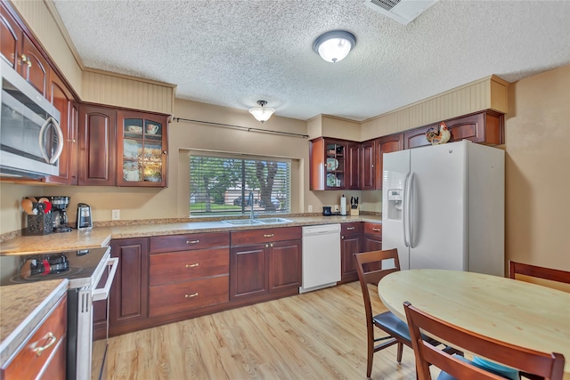 16426 Cavendish Dr, Houston, TX 77059 - kitchen featuring stainless steel appliances, a textured ceiling, light wood finished floors, light countertops, and glass insert cabinets