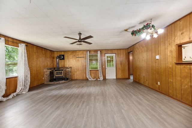 423 Pouland St, Zavalla, TX 75980 - unfurnished living room featuring a wood stove, wood finished floors, a ceiling fan, and wooden walls
