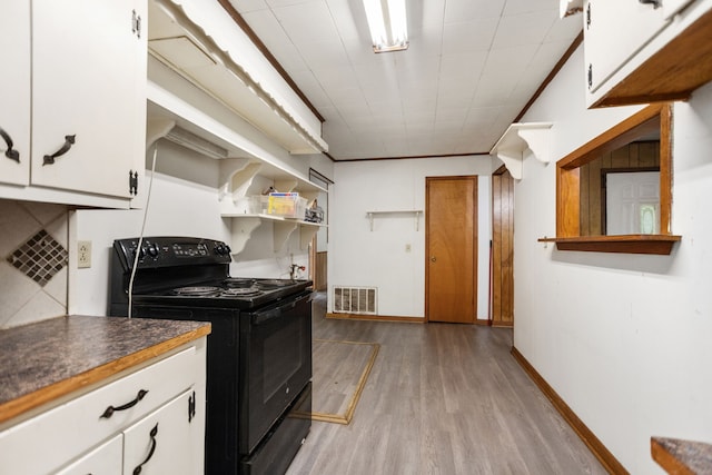 423 Pouland St, Zavalla, TX 75980 - kitchen featuring black range with electric cooktop, light wood finished floors, white cabinets, and open shelves