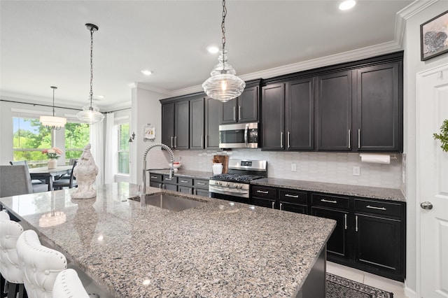 3447 Warwick River Trl, Kingwood, TX 77365 - kitchen featuring appliances with stainless steel finishes, crown molding, decorative backsplash, a kitchen island with sink, and light stone countertops