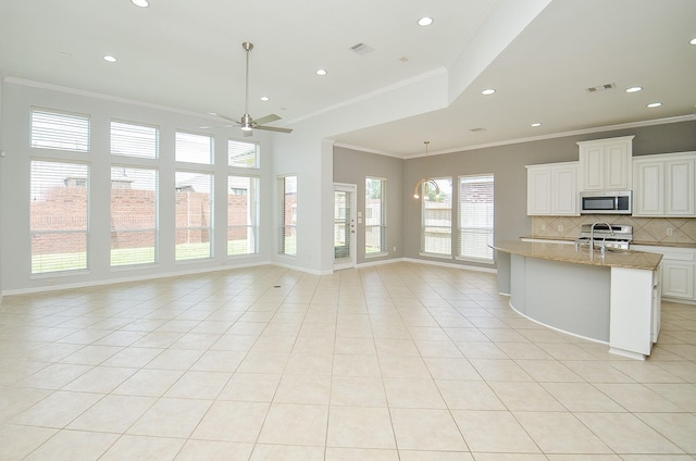 3910 Jade Cove Ln, Sugar Land, TX 77479 - kitchen with stainless steel microwave, open floor plan, backsplash, light tile patterned floors, and ceiling fan