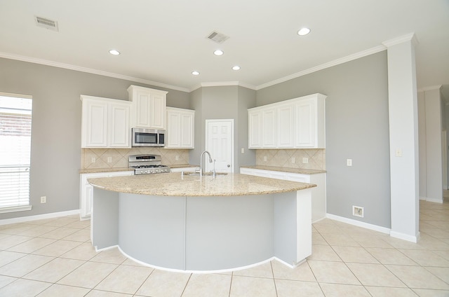 3910 Jade Cove Ln, Sugar Land, TX 77479 - kitchen with stainless steel microwave, white range with gas cooktop, light tile patterned floors, decorative backsplash, and an island with sink